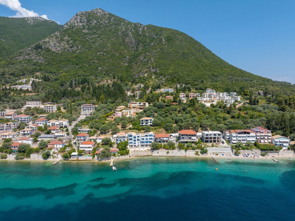 Vista della costa di Perigiali dal mare con il Greek Beach House al centro, immerso tra acque dai colori smeraldini e sfumature turchesi.