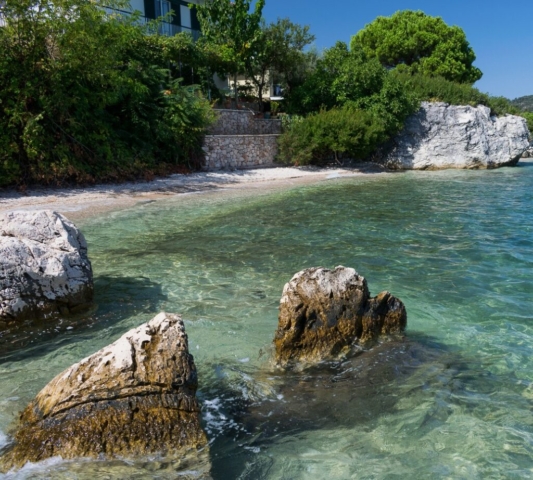 Vista di una casa situata direttamente sulla spiaggia a Nikiana, circondata da un paesaggio costiero tranquillo.