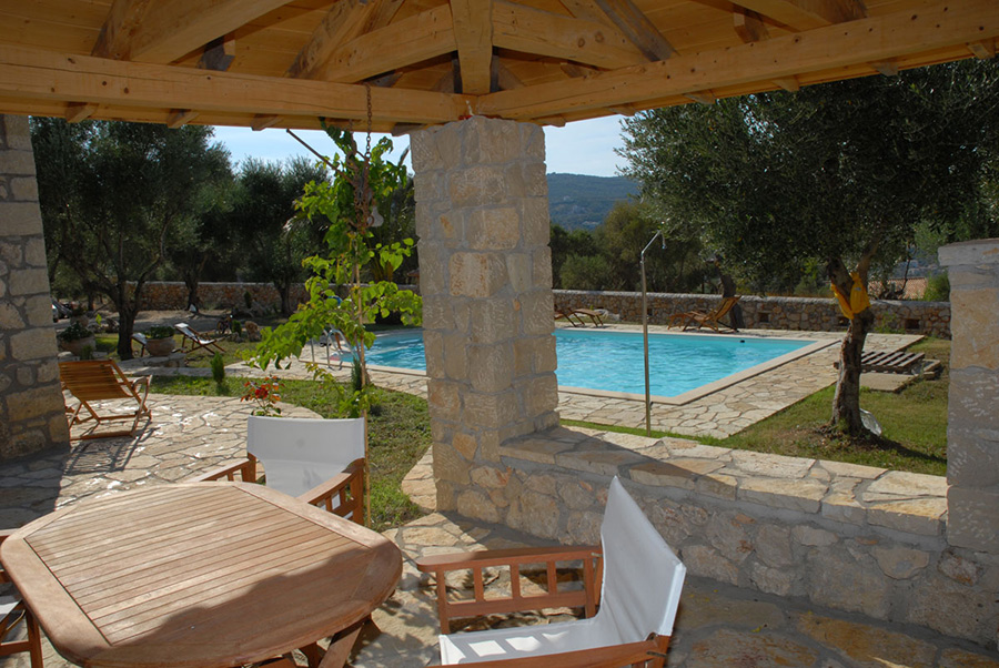 Vista della piscina e del giardino mediterraneo dal patio in ombra.