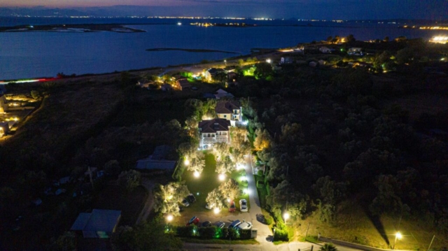 Vista notturna aerea di Niki Apts ad Agios Ioannis, catturata da un drone, che mostra il complesso illuminato e il grande giardino circostante.