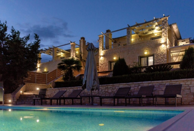 Le Ionian Diamond Villas all’imbrunire, con le luci accese che creano un’atmosfera suggestiva mentre la notte avvolge la baia.