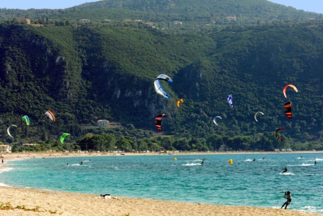 Kite surfing in azione ad Agios Ioannis, con il promontorio che domina lo sfondo.