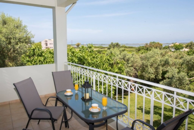 Spazioso balcone dell'appartamento con una camera da letto al primo piano di Niki Apts, con vista sul giardino e sull'area circostante ad Agios Ioannis.